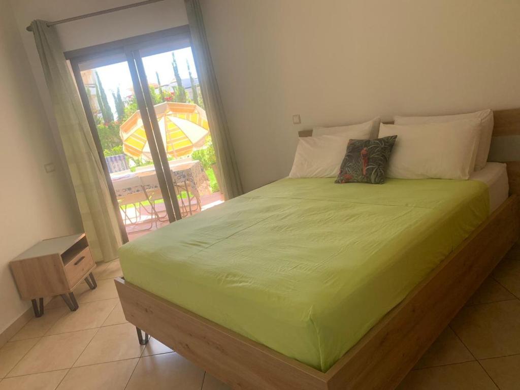 a bedroom with a bed with a green comforter and a window at Beralmar Asilah Chez FATIMA in Asilah