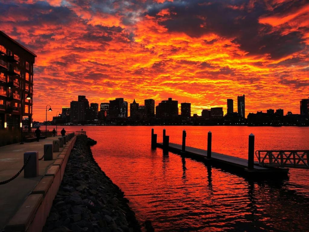 una puesta de sol sobre un cuerpo de agua con una ciudad en Location+Comfort+Convenience en Boston