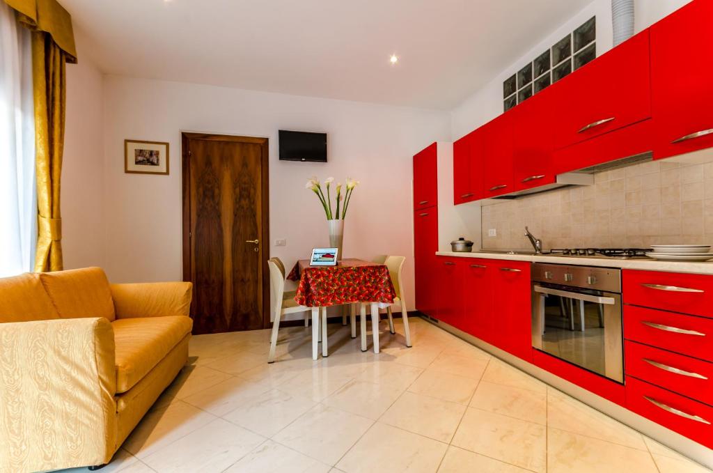 a kitchen with red cabinets and a table and a couch at Cannaregio II Apartments in Venice