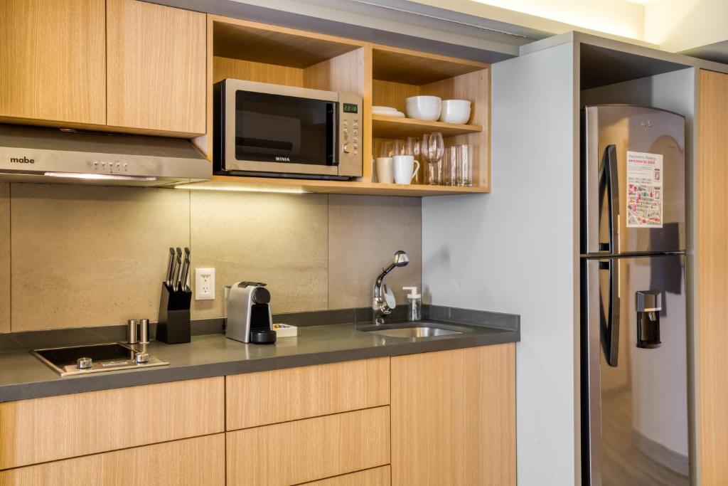 A compact kitchenette with full-size refrigeration and basic cooking equipment.