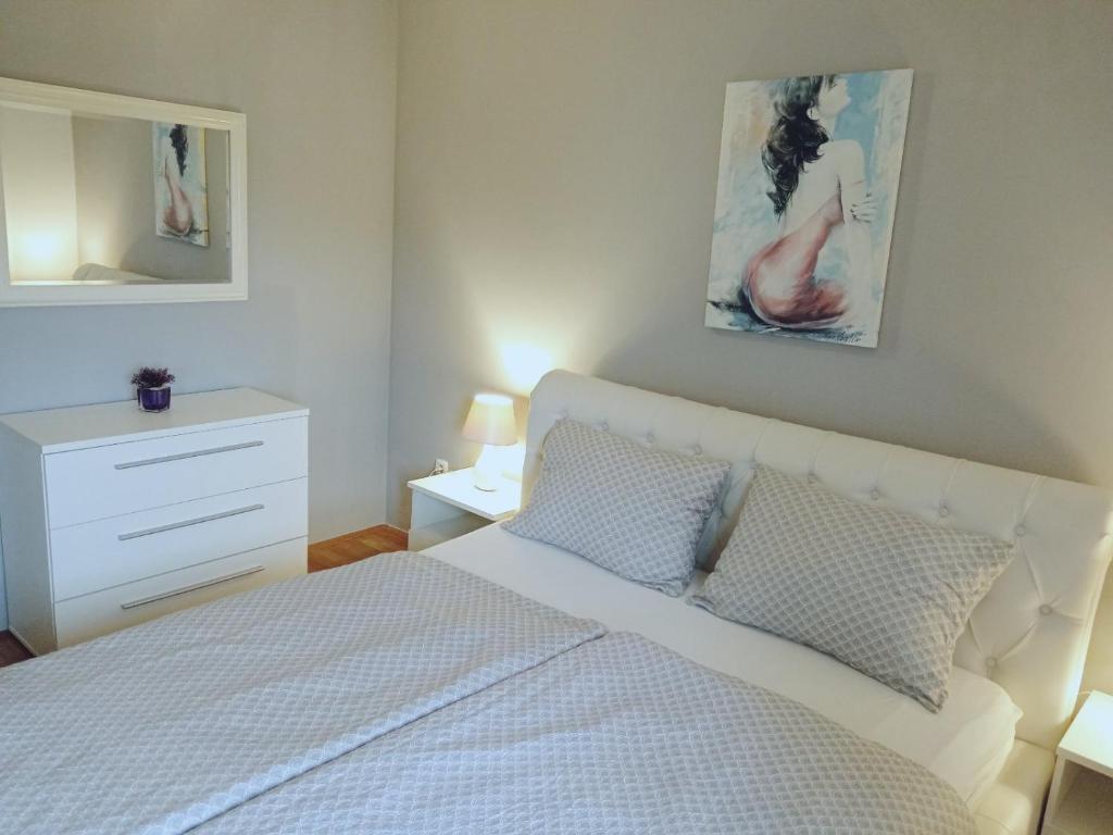 a bedroom with a white bed and a dresser at Apartment Anita in Umag