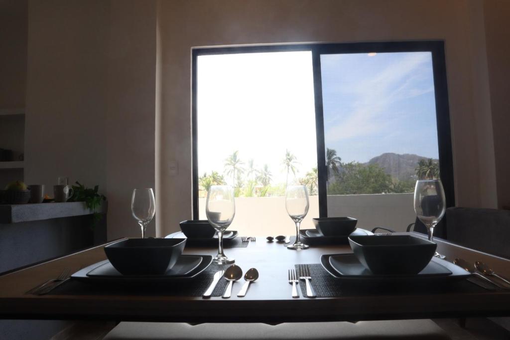 une table à manger avec des verres et des assiettes ainsi qu'une fenêtre dans l'établissement Happy tower, à Barra de Navidad