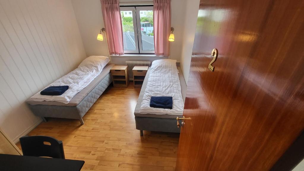 a room with two beds and a table with a window at Heart of the City (Hotel Bólið Guesthouse) in Tórshavn