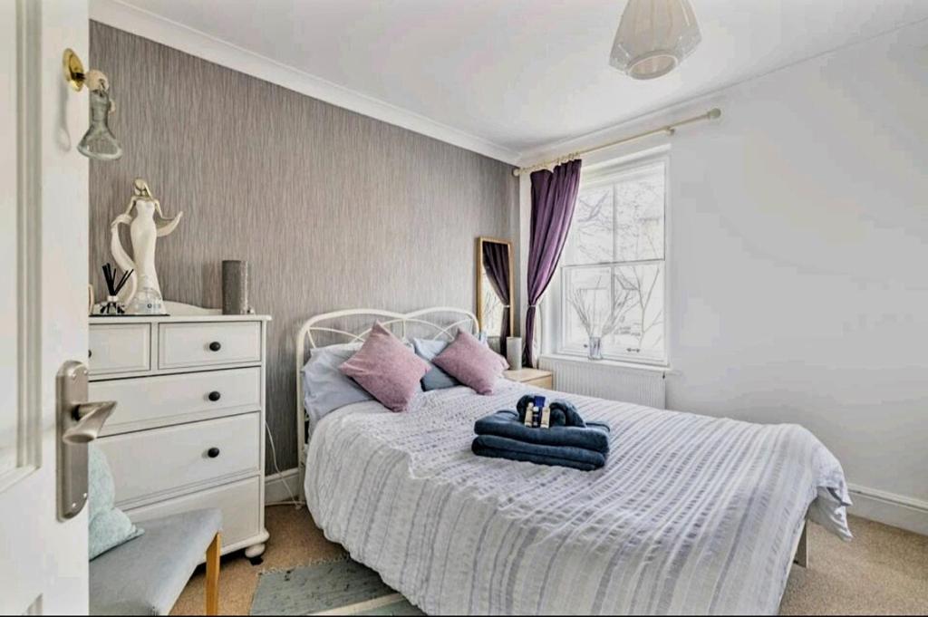 a bedroom with a white bed with purple pillows at The Mews in Cardiff