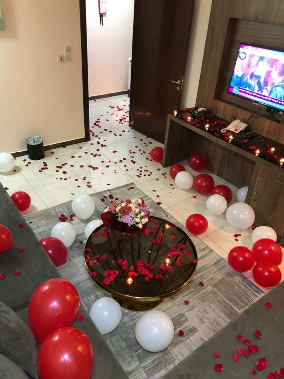 ein Zimmer mit roten und weißen Ballons und einem Kuchen auf dem Boden in der Unterkunft منازل الساهر للوحدات المخدومة فرع 2 in Al Qunfudhah