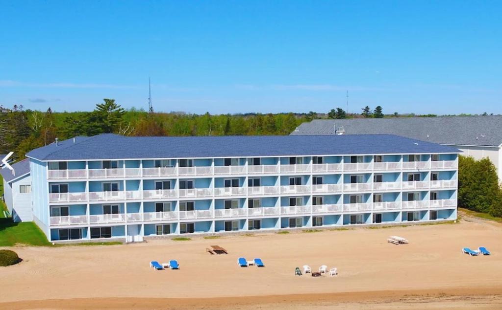 a hotel on the beach with chairs on the beach at Great Mackinaw Beachfront Hotel in Mackinaw City