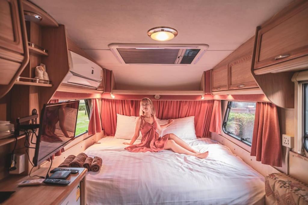 una mujer sentada en una cama en una caravana en (01)The Height Khaoyai/ camper-van /Pool&Gym en Ban Huai Sok Noi