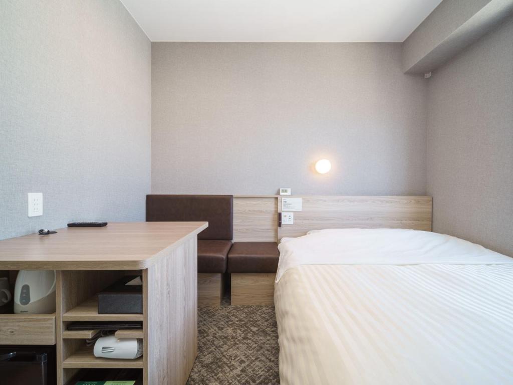 藤沢市にあるスーパーホテル 湘南・藤沢駅南口のベッドとデスクが備わる小さな客室です。