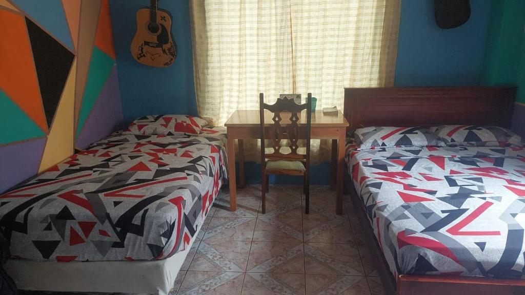 - une chambre avec 2 lits et une table avec une guitare dans l'établissement C.C. Habitaciones, à Puerto Baquerizo Moreno