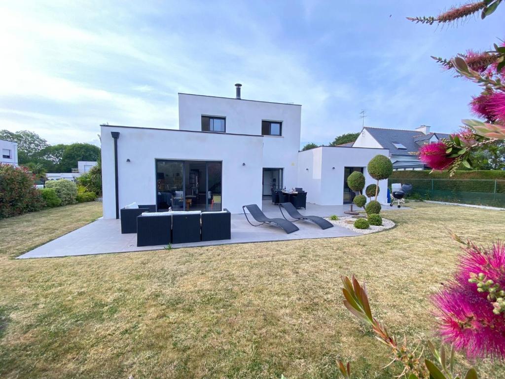 une maison blanche avec un mobilier noir dans une cour dans l'établissement Comfortable holiday villa in a quiet location in Bénodet, à Bénodet