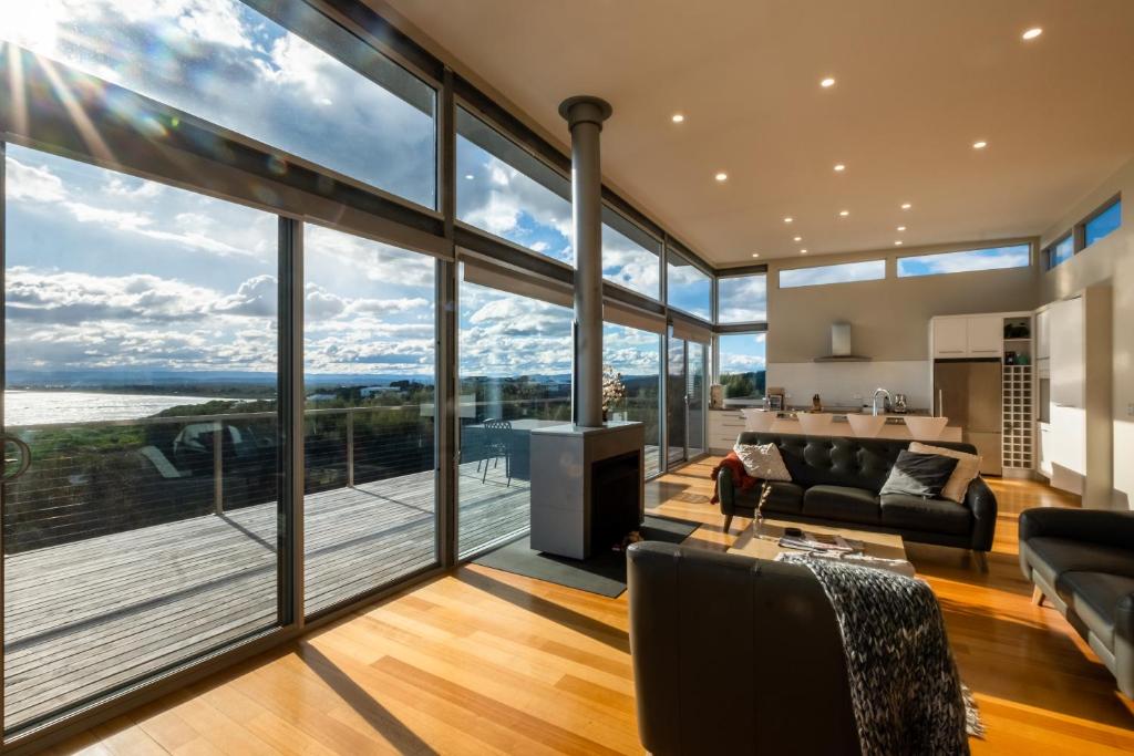a living room with large windows and a view of the water at Halcyon ~ Immerse yourself in the sky and sea in Coles Bay