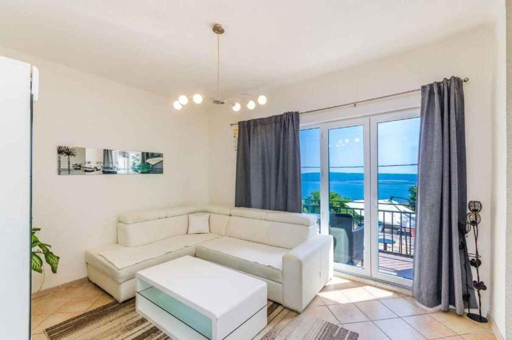 a living room with a white couch and a large window at Apartment in Dramalj 44160 in Dramalj