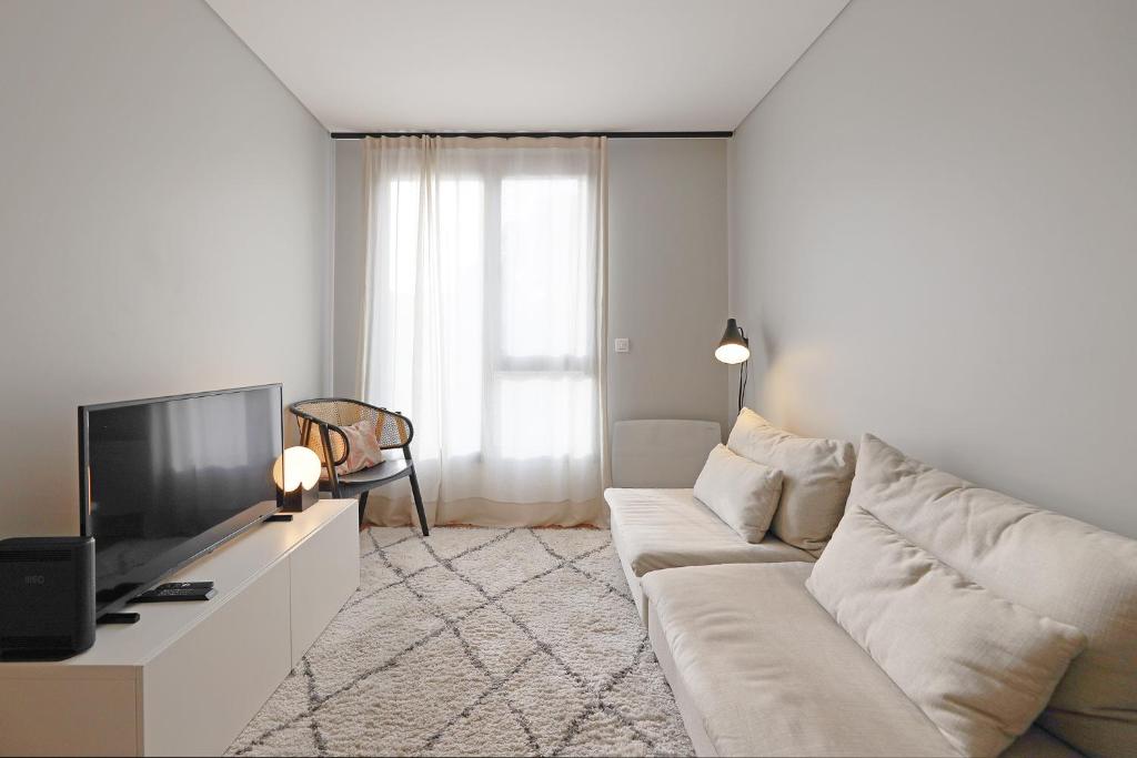 sala de estar con sofá blanco y TV en FLH Boavista Flat III en Oporto
