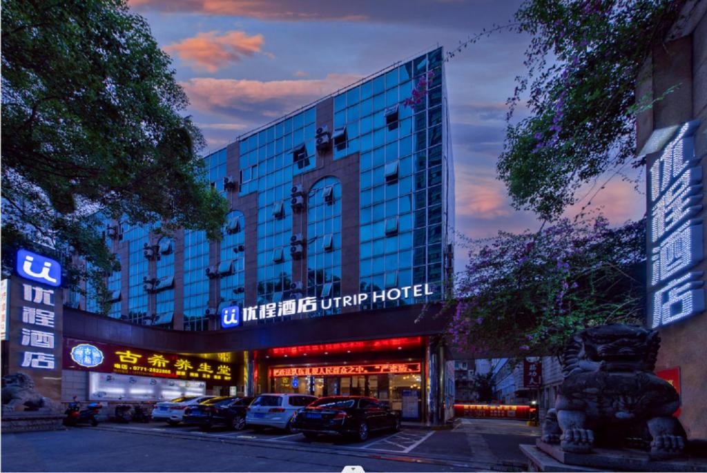 un edificio con auto parcheggiate di fronte di Unitour Hotel, Nanning Jianzheng a Nanning