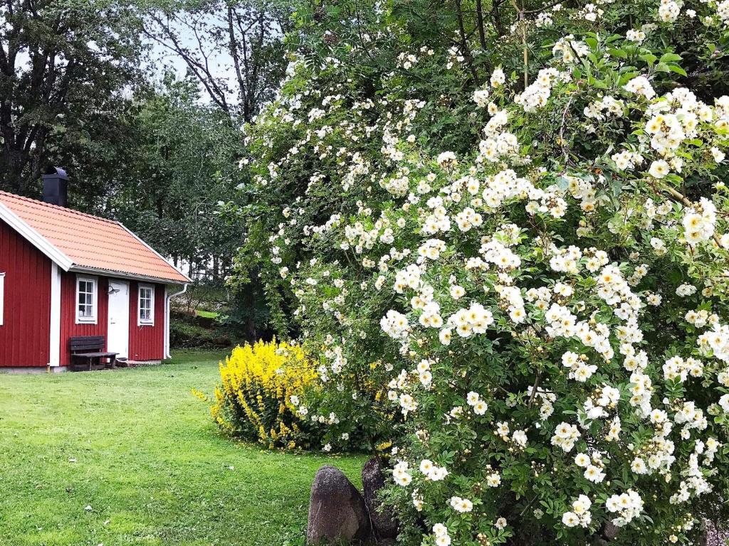 a large bush of flowers in front of a red house at 4 person holiday home in FALKÖPING-By Traum in Falköping