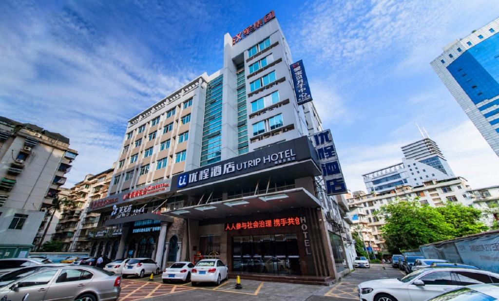 a tall building with cars parked in a parking lot at Unitour Hotel, Nanning Dongge Traditional Chinese Medicine No 1 Affiliated in Nanning