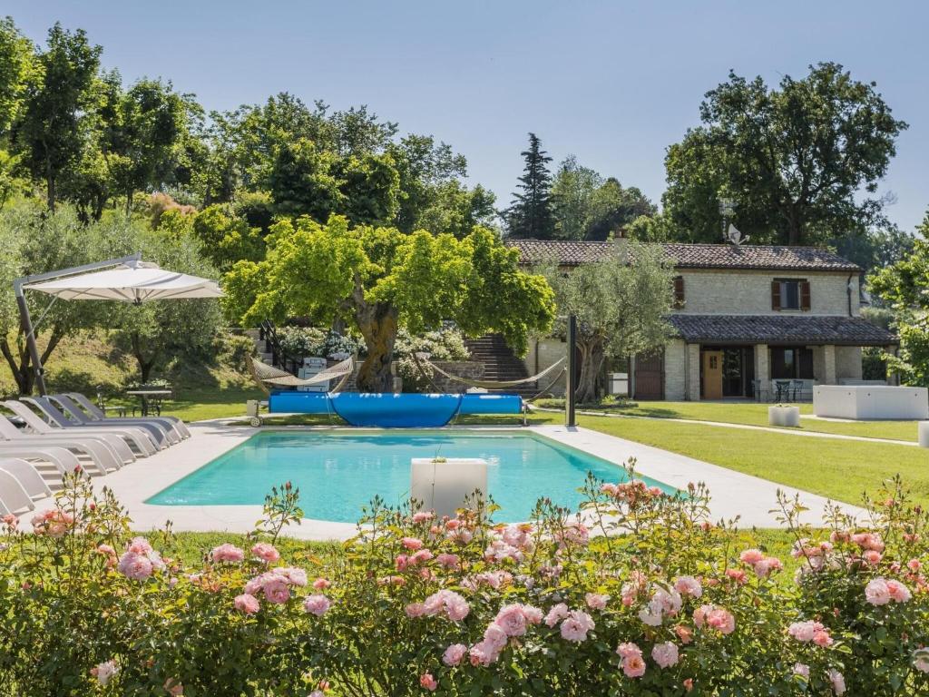 a pool in the backyard of a house with flowers at Belvilla by OYO Villa Anna in SantʼIppolito
