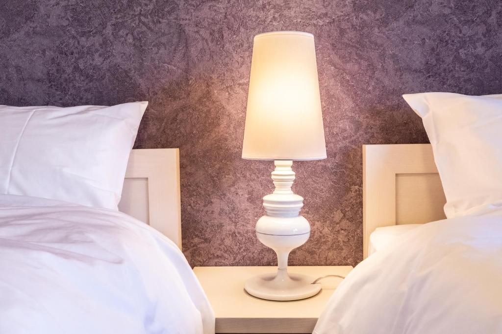 una lámpara blanca sentada en una mesita de noche entre dos camas en ルグランみしま, en Hamamatsu