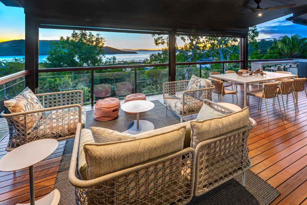 a deck with tables and chairs and a view of the ocean at Point Blue on Hamilton Island by HIHA in Hamilton Island
