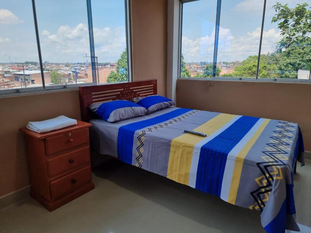 a bedroom with a bed and a dresser with windows at Picuro Lodging House in Iquitos
