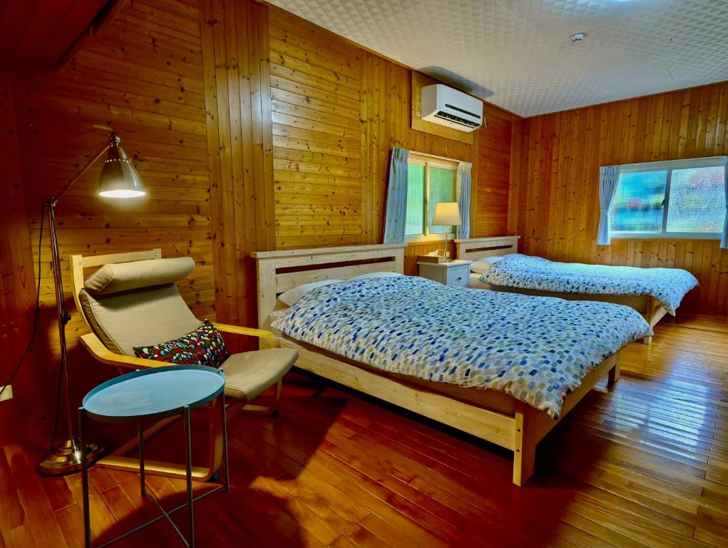 a bedroom with two beds and a chair at Fong Chou Chalet in Sanyi