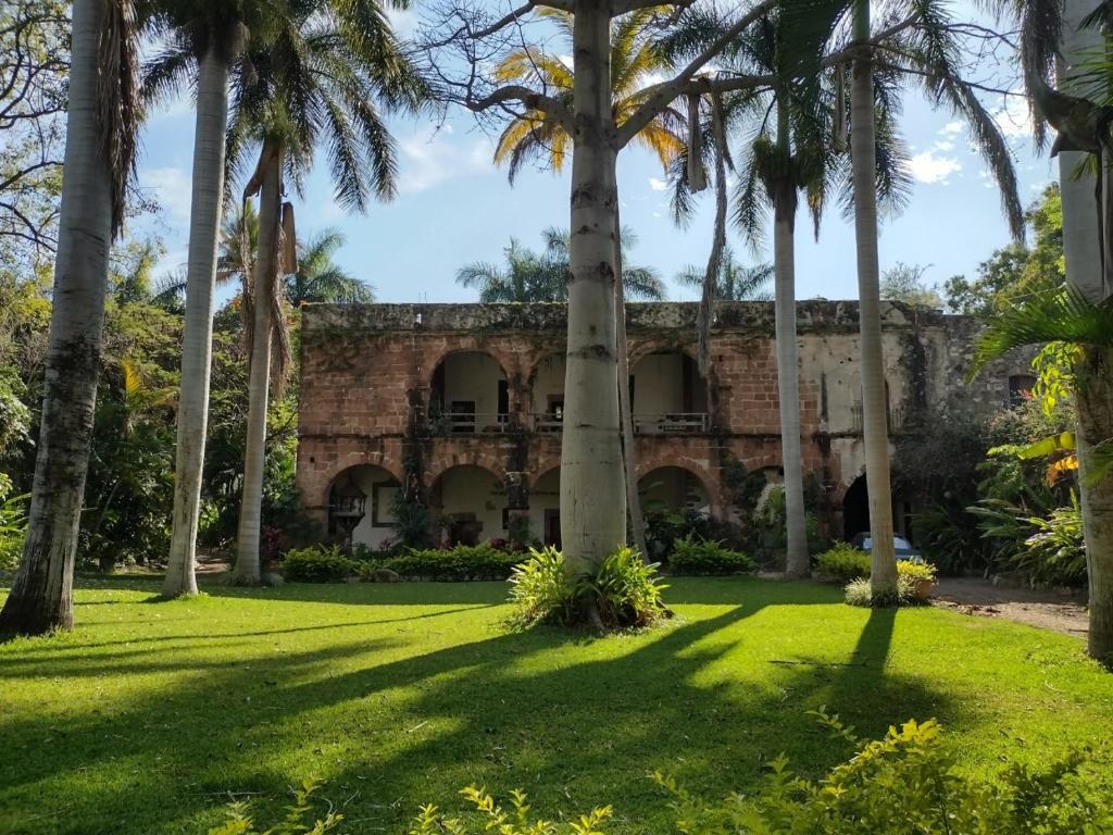 un antiguo edificio de piedra con palmeras en el patio en Hacienda la Luna, 