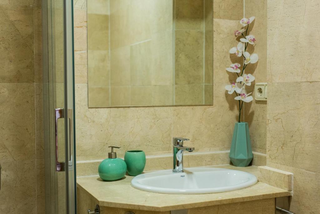 a bathroom sink with two vases and a mirror at Toledo Enamora Dos - PARKING INCLUIDO in Toledo