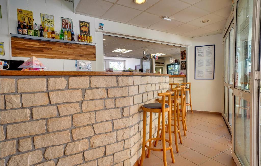 a brick wall with stools at a bar at 2 Bedroom Beautiful Home In La Faute-sur-mer in La Faute-sur-Mer