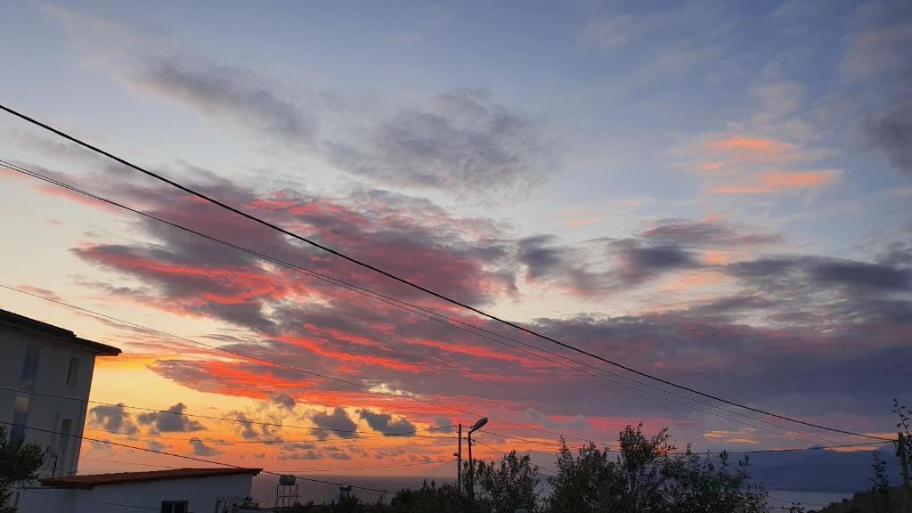a sunset with red clouds in the sky at Mihal Suites in Sarandë