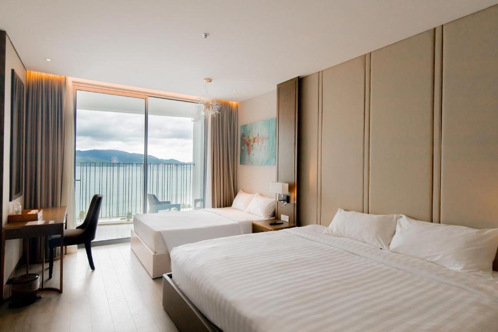 a hotel room with two beds and a desk and a window at Highsea Panorama Nha Trang Apartments in Nha Trang