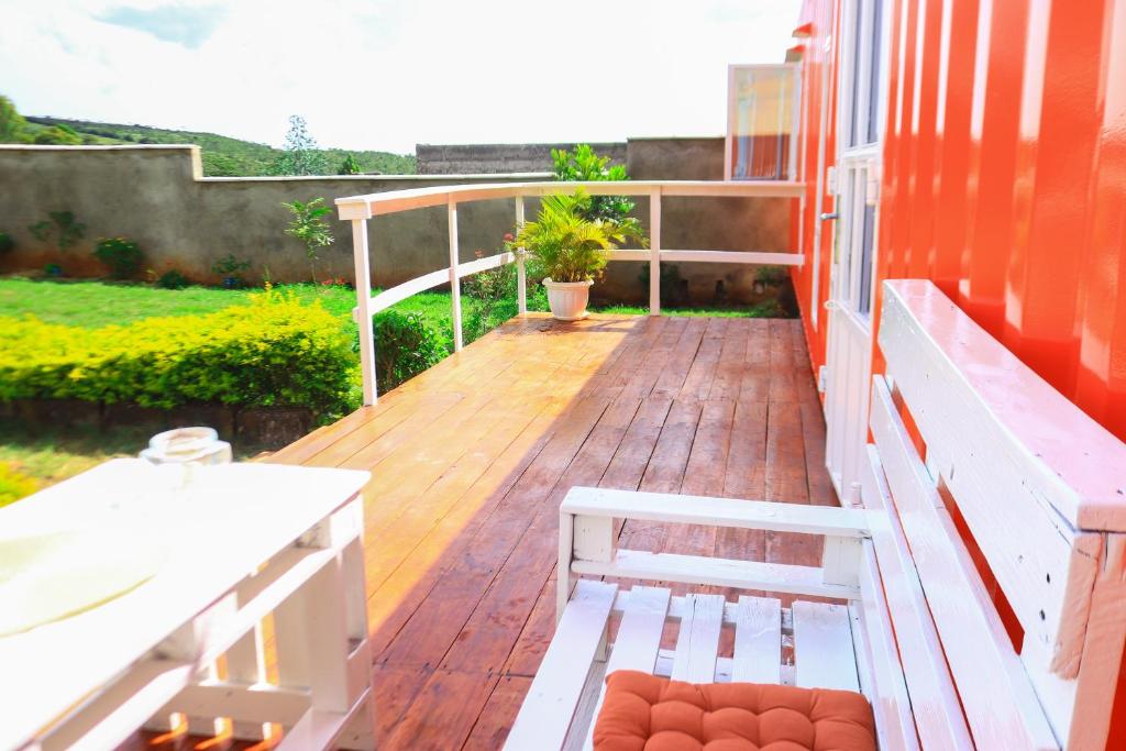 a wooden deck with a bench on a house at The Red Container-Off Grid in Ngong