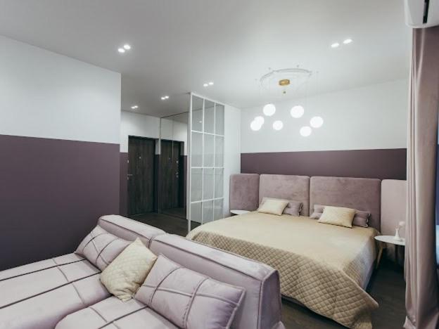 a bedroom with a bed and a couch at Atlant luxury VIOLET Apart on Golovna стильні апартаменти поряд з ТЦ ДЕПОТ БЕЗКОНТАКТНЕ ЗАСЕЛЕННЯ in Chernivtsi