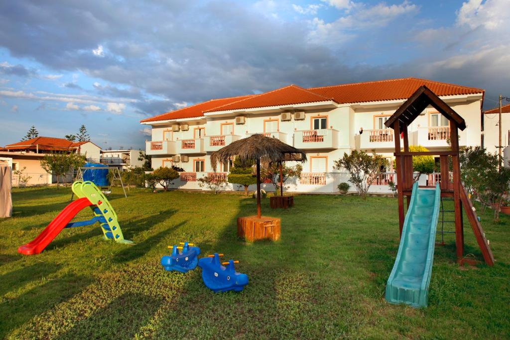 a yard with playground equipment in front of a building at Akis Studios Alykes in Alykes