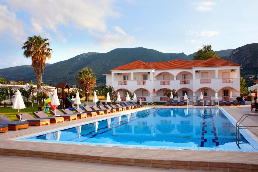 a hotel with a swimming pool with chairs and a building at Akis Studios Alykes in Alykes
