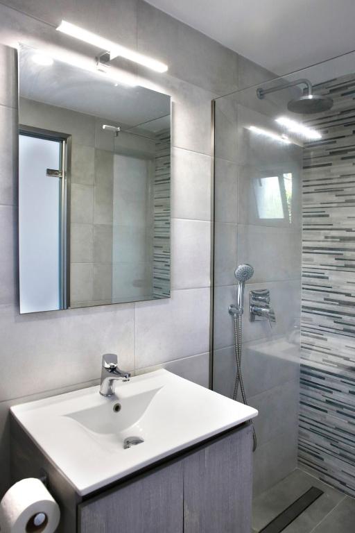a bathroom with a sink and a shower with a mirror at Akis Studios Alykes in Alykes