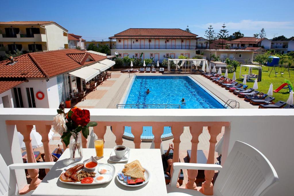 a balcony with a table with food and a pool at Akis Studios Alykes in Alykes