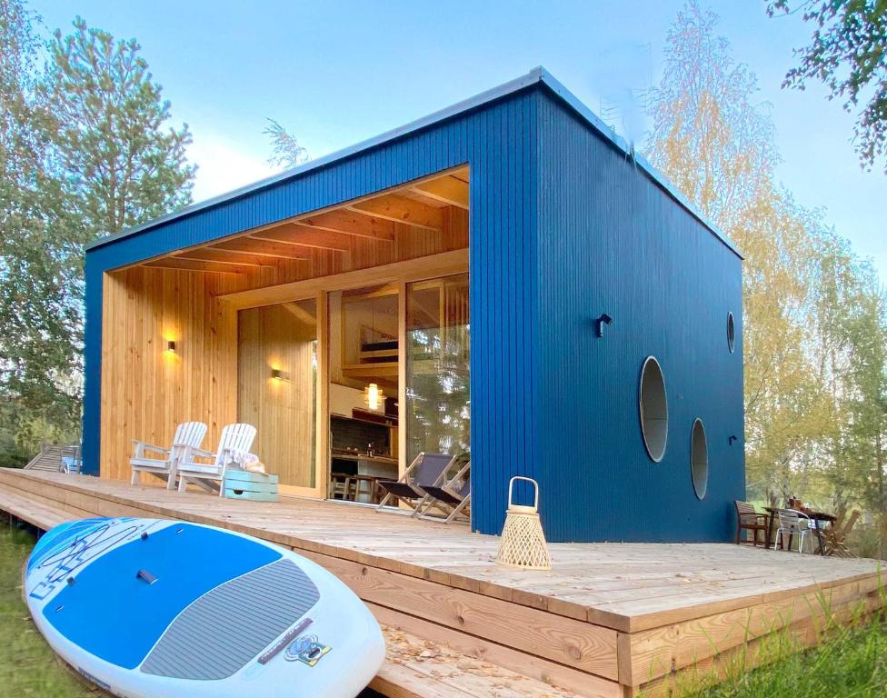 uma casa azul com uma prancha de surf no convés em Lunette Lodge am See mit Sauna für 10 Gäste em Brzozie