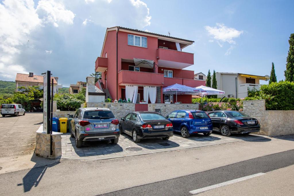 a group of cars parked in front of a red building at Apartments Mare in Punat