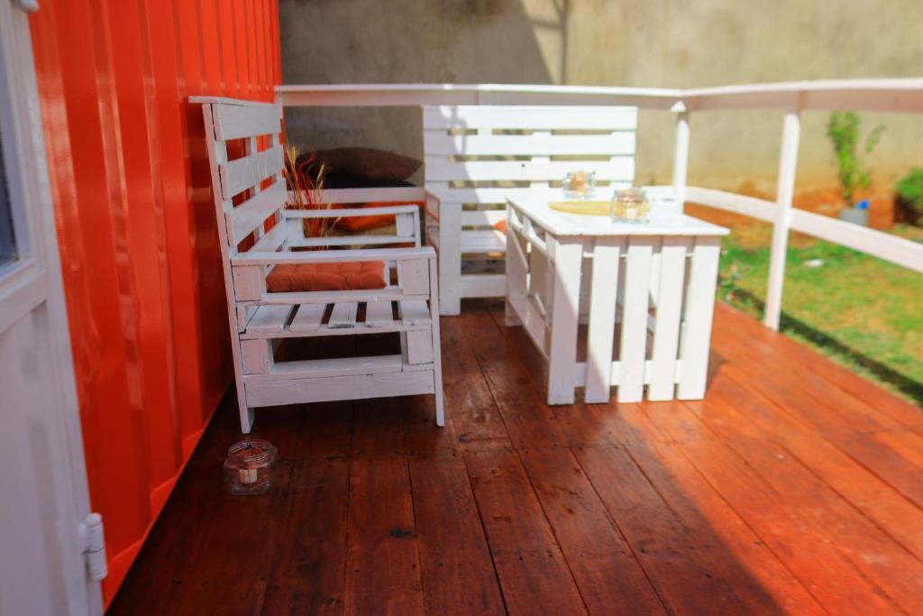 a porch with two chairs and a table on a deck at The Red Container-Off Grid in Ngong