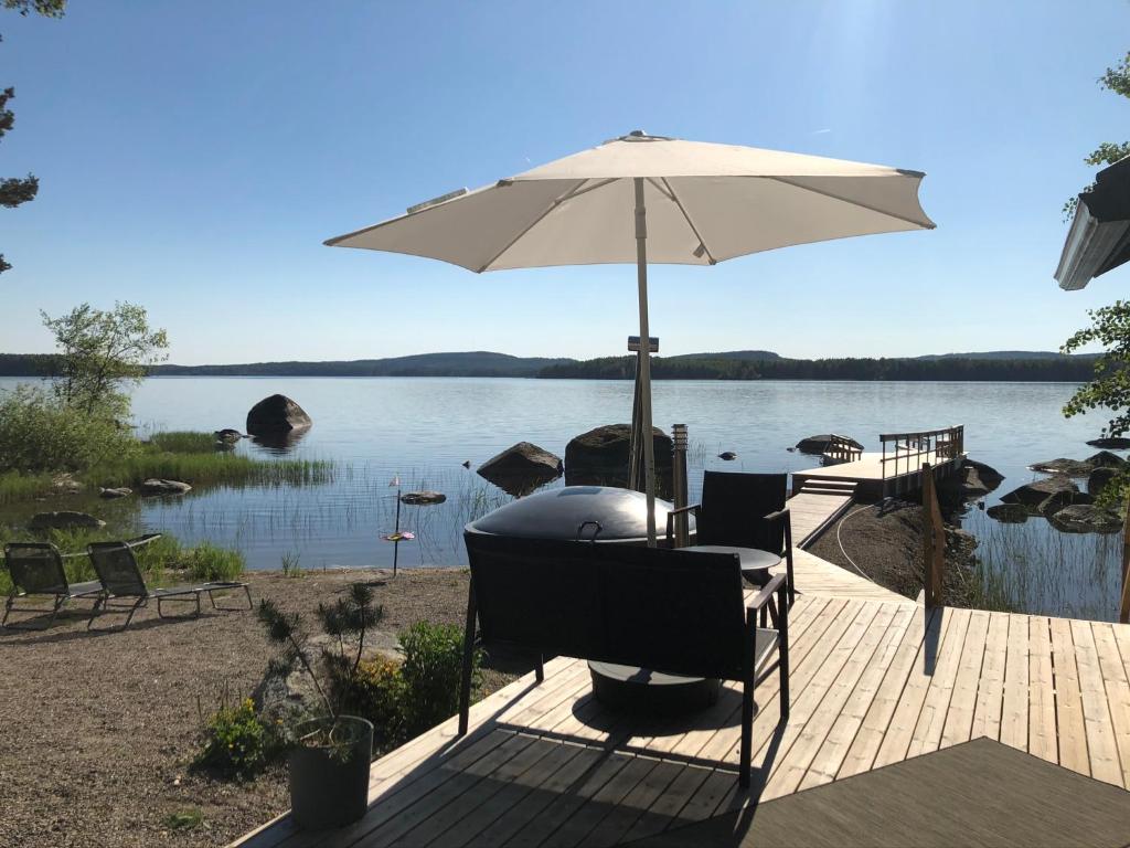 a table with an umbrella on a deck next to a lake at Kesämökki Tanela in Leppälahti