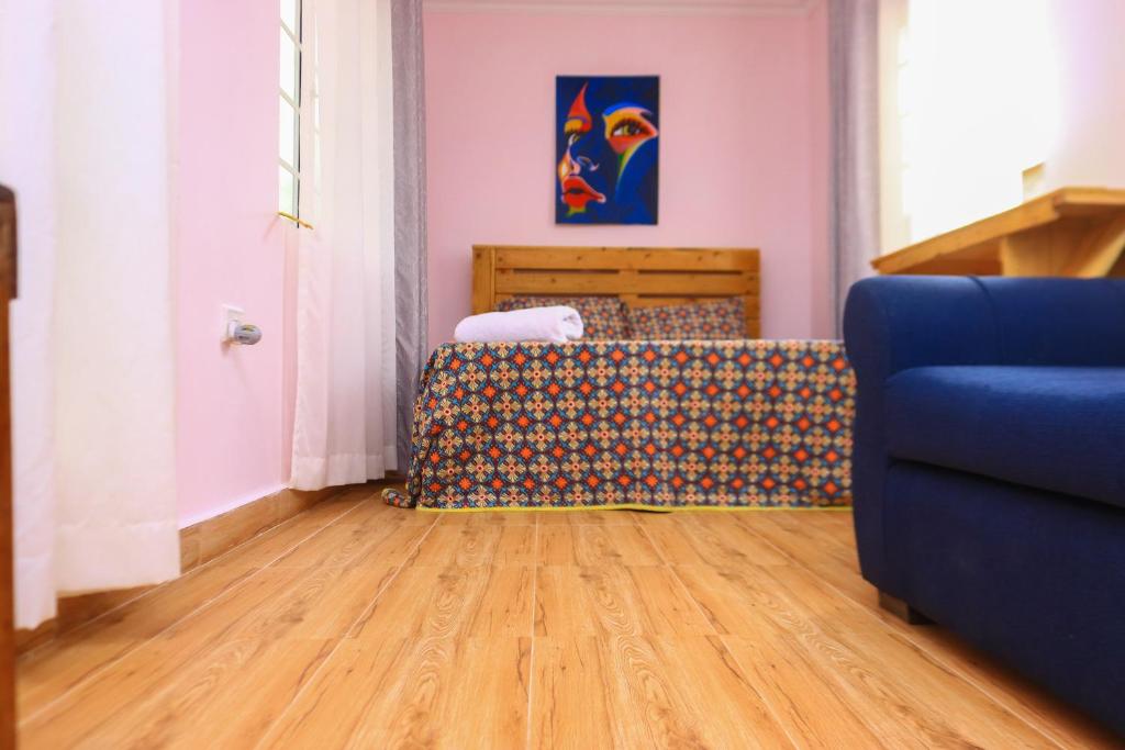 a living room with a blue couch and wooden floors at The Red Container-Off Grid in Ngong