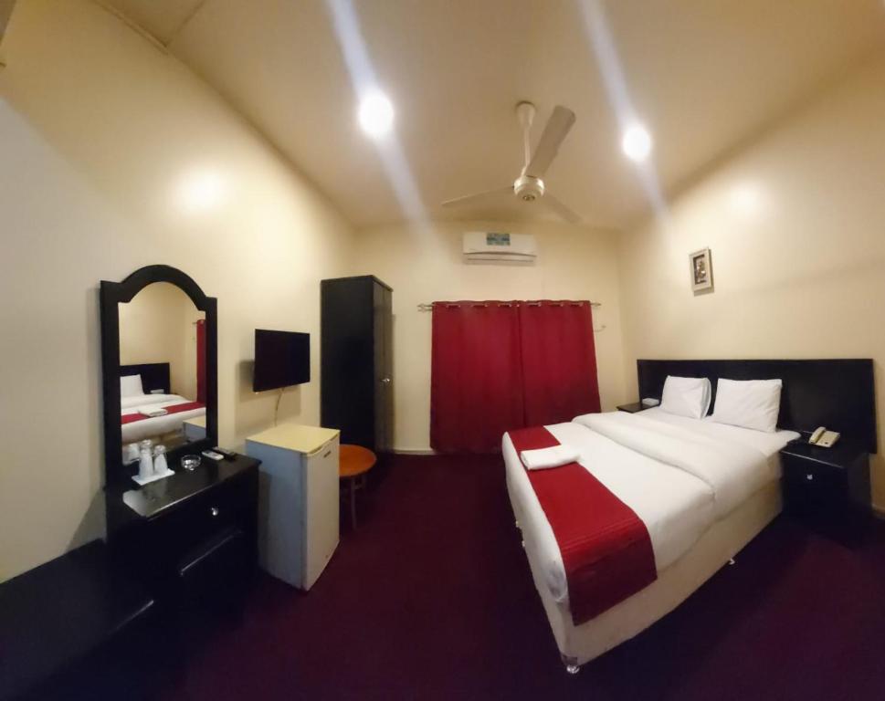 1 dormitorio con 1 cama grande y cortina roja en DANA HOTEL, en Sharjah