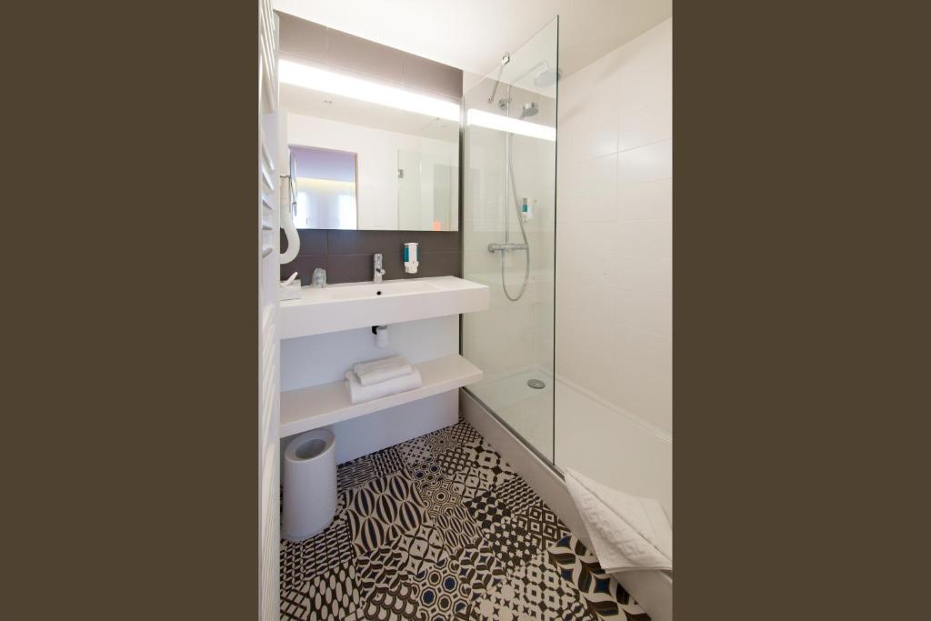 a bathroom with a sink and a shower with a mirror at La Regence in Courbevoie