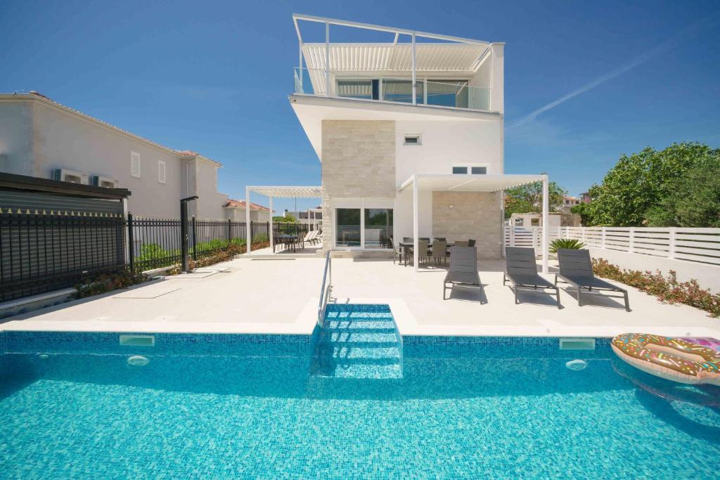 a house with a swimming pool in front of a house at Pinia Apartments in Vodice