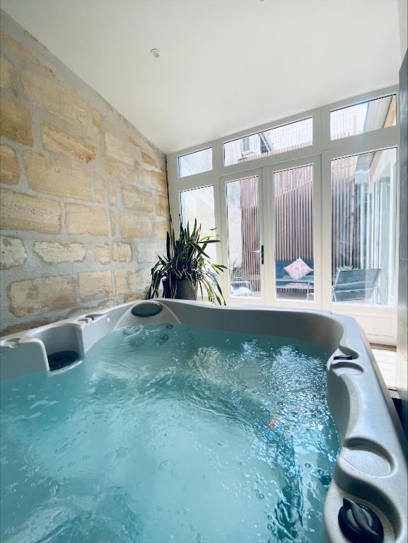 une grande baignoire dans une pièce avec une grande fenêtre dans l'établissement La King Le 50 Suites and SPA, à Bordeaux
