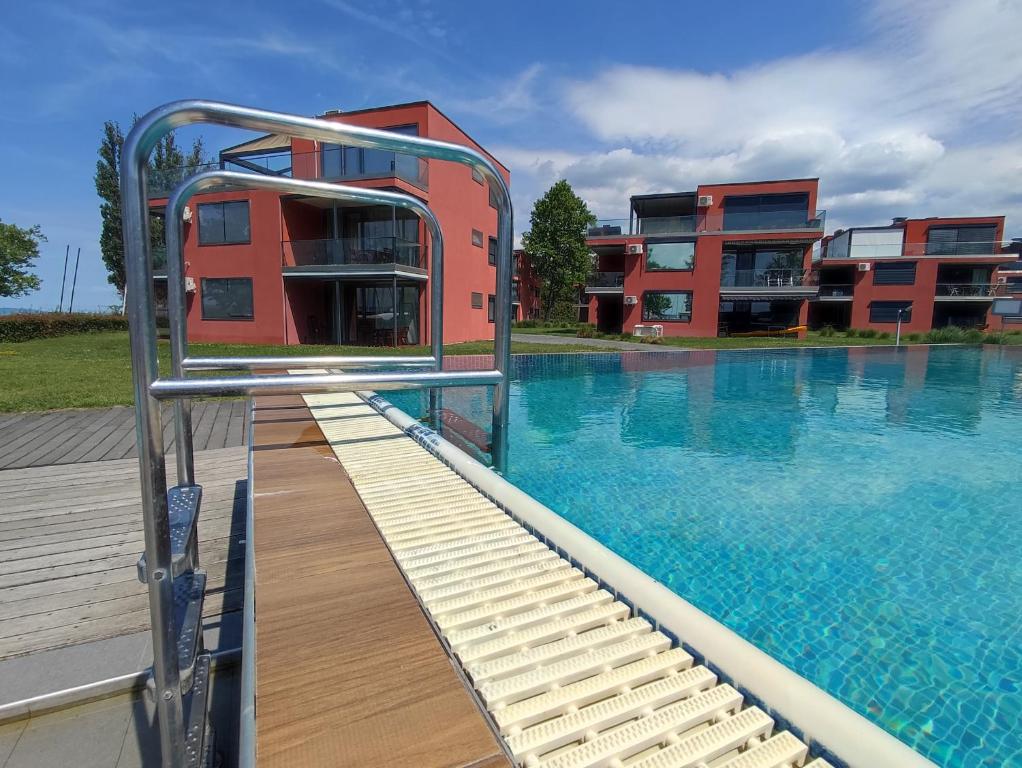 a building with a swimming pool next to a building at Soleil Apartmanok Balatonlelle in Balatonlelle