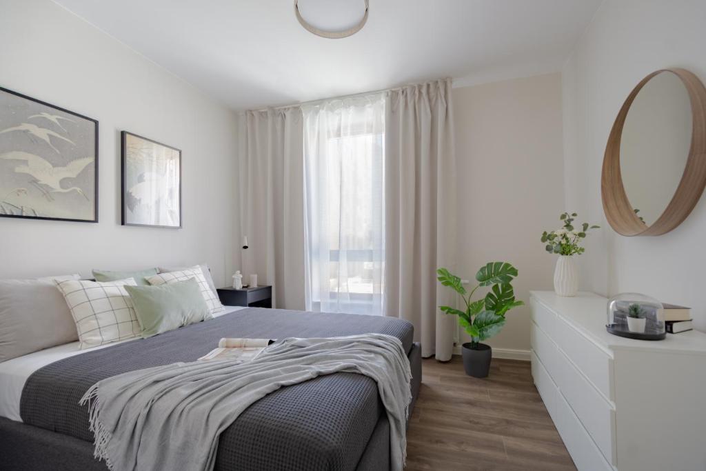 - une chambre blanche avec un lit et un miroir dans l'établissement Roomsy - Scala, à Gdańsk