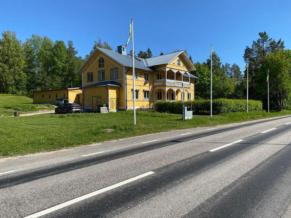 una casa amarilla al lado de una carretera en Lokatten Wärdshus en Los