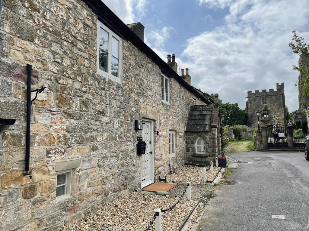 um antigo edifício de pedra com uma porta branca em The Little Chantry - Hot Tub, Riverside, Pet Friendly em West Tanfield