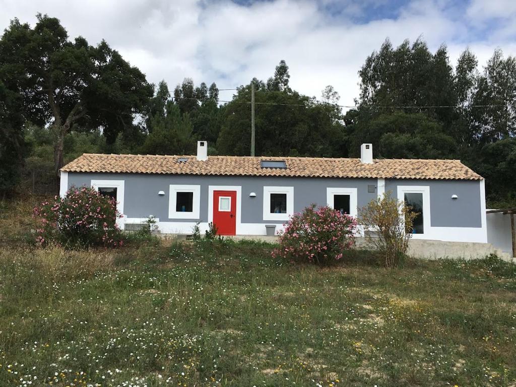 a white house with a red door in a field at Monte Teu in São Luis